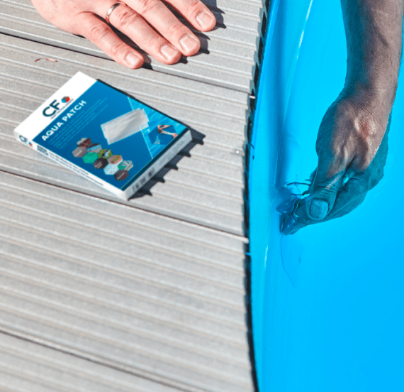 En närbild i en pool eller trädgårdsdamm som visar hur en genomskinlig patch appliceras på linern för att stoppa en läcka.